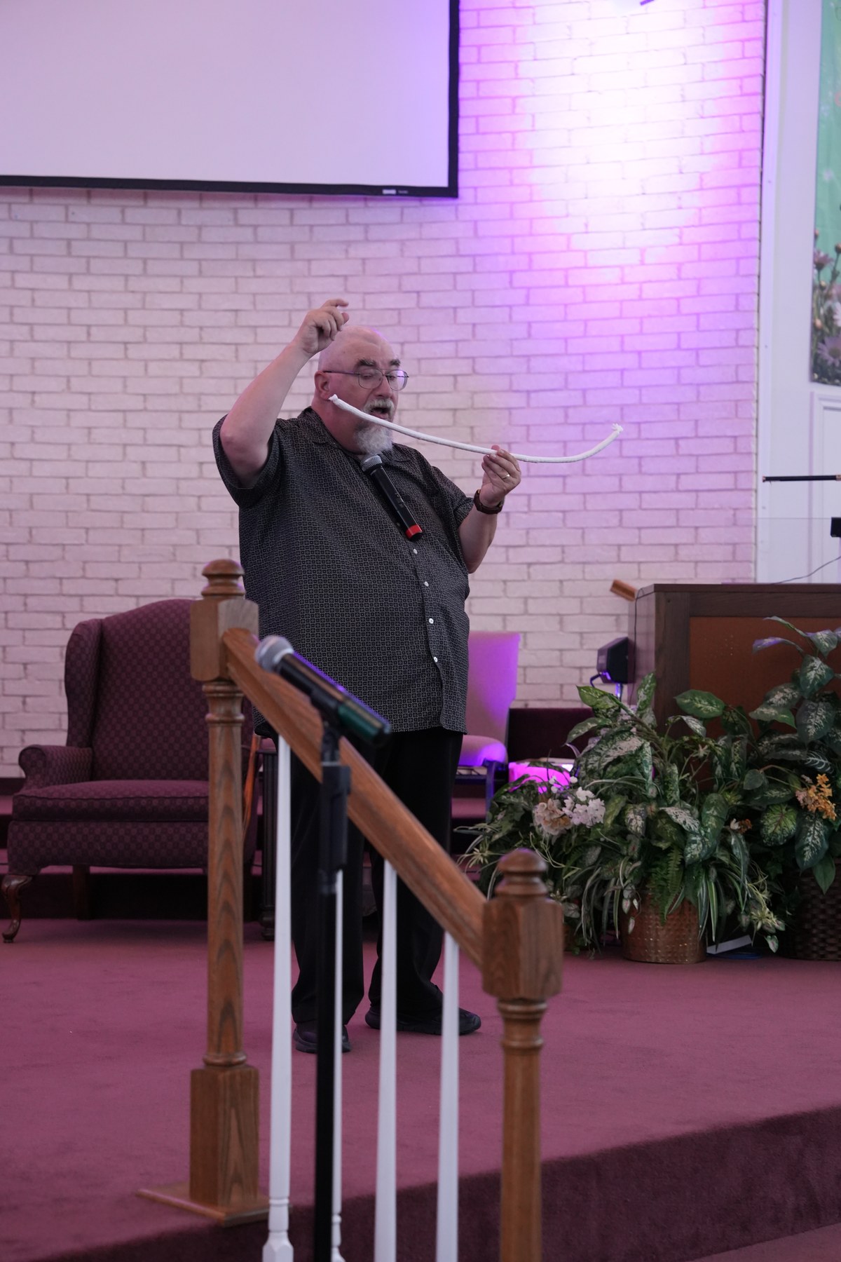 Ken Sibley presenting a Gospel illusion with a silk scarf on stage